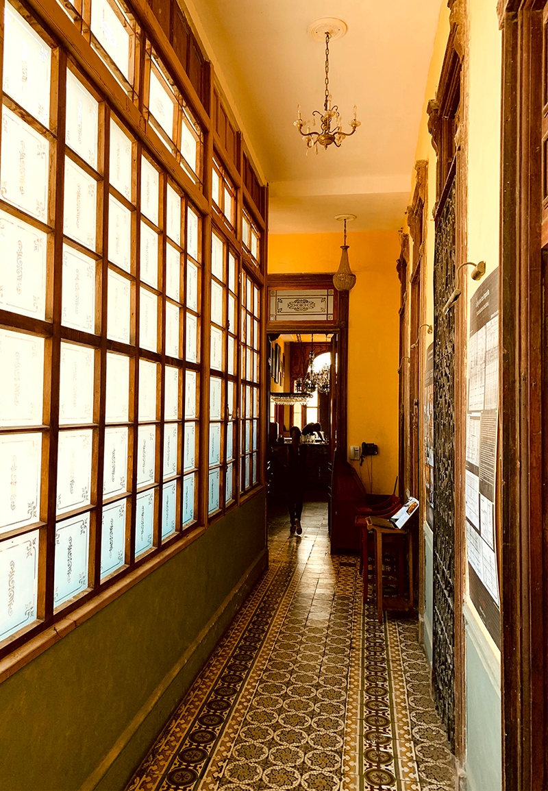 A hallway lined with windows and patterned floor tiles 