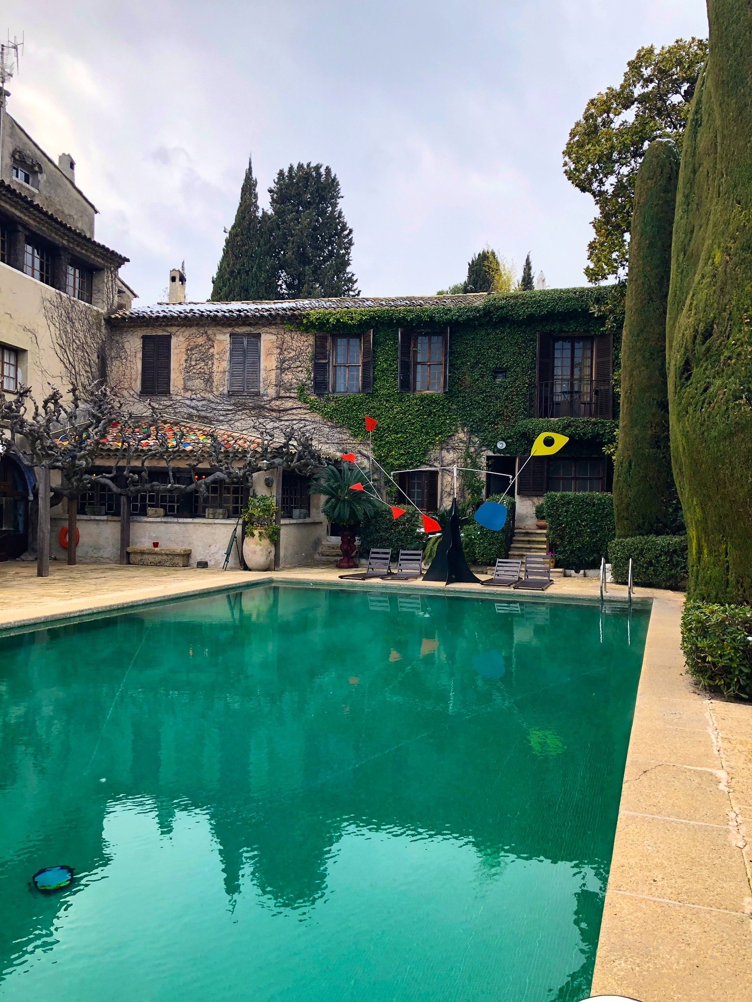 By the pool at La Colombe D’or, surrounded by vine covered buildings and tall trees 