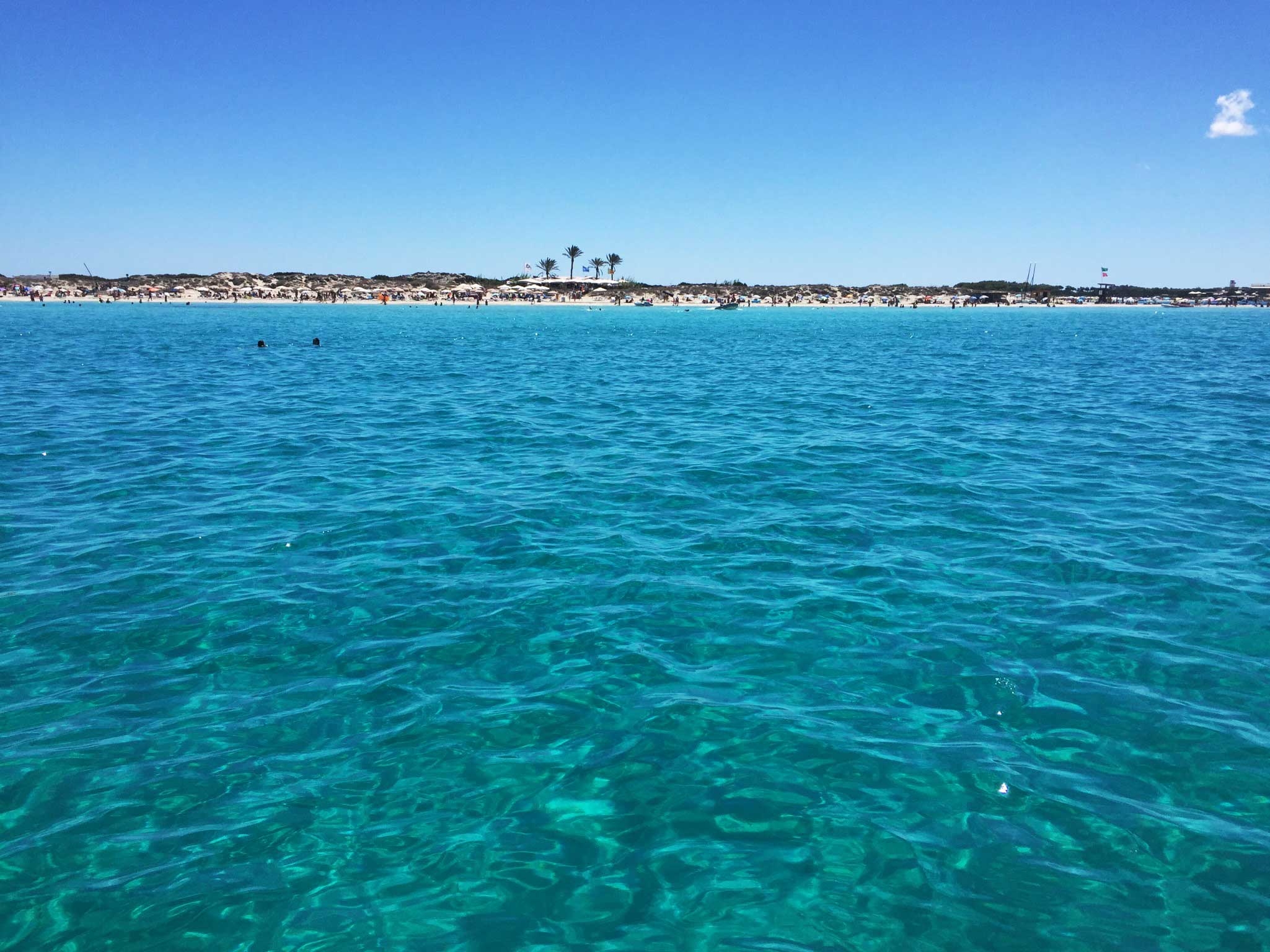 Looking to the Formentera coast from a boat on the bright turquoise ocean 