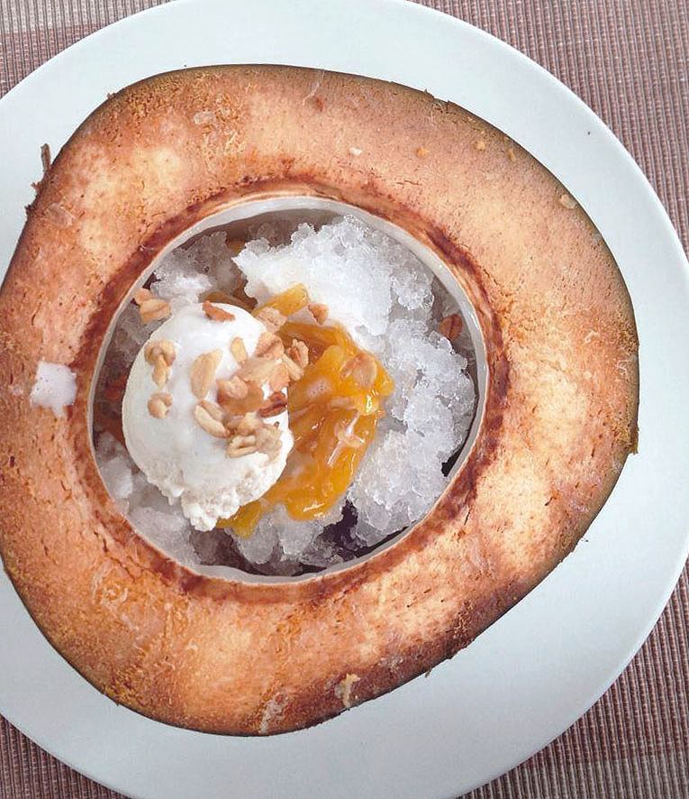 Filipino dessert, Halo Halo, is crushed ice served in a coconut, topped with ice cream, fruit and evaporated milk 