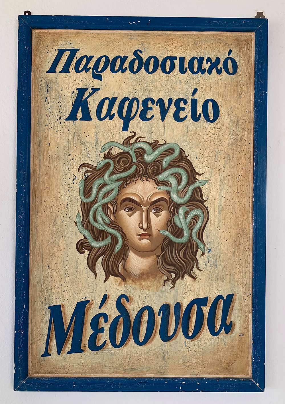 A Greek sign at Medousa Restaurant in Mandrakia, with a hand painted take of Medusa. “Simple, Traditional and Delicious”. 