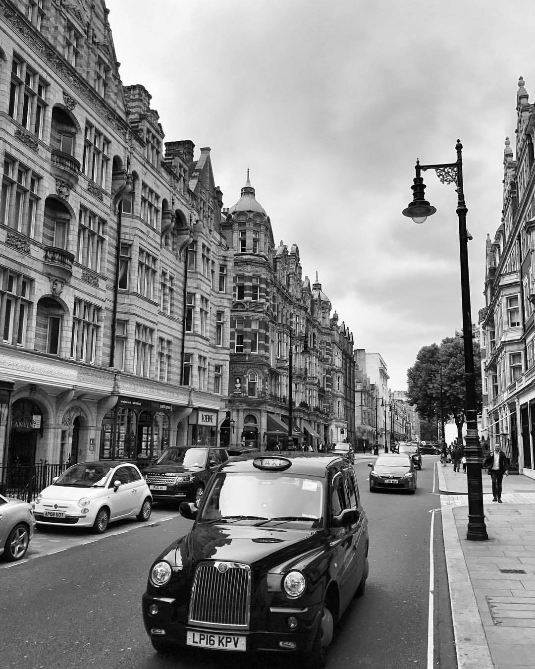 A gloomy day on Mount Street with cars passing by English baroque architectural buildings 