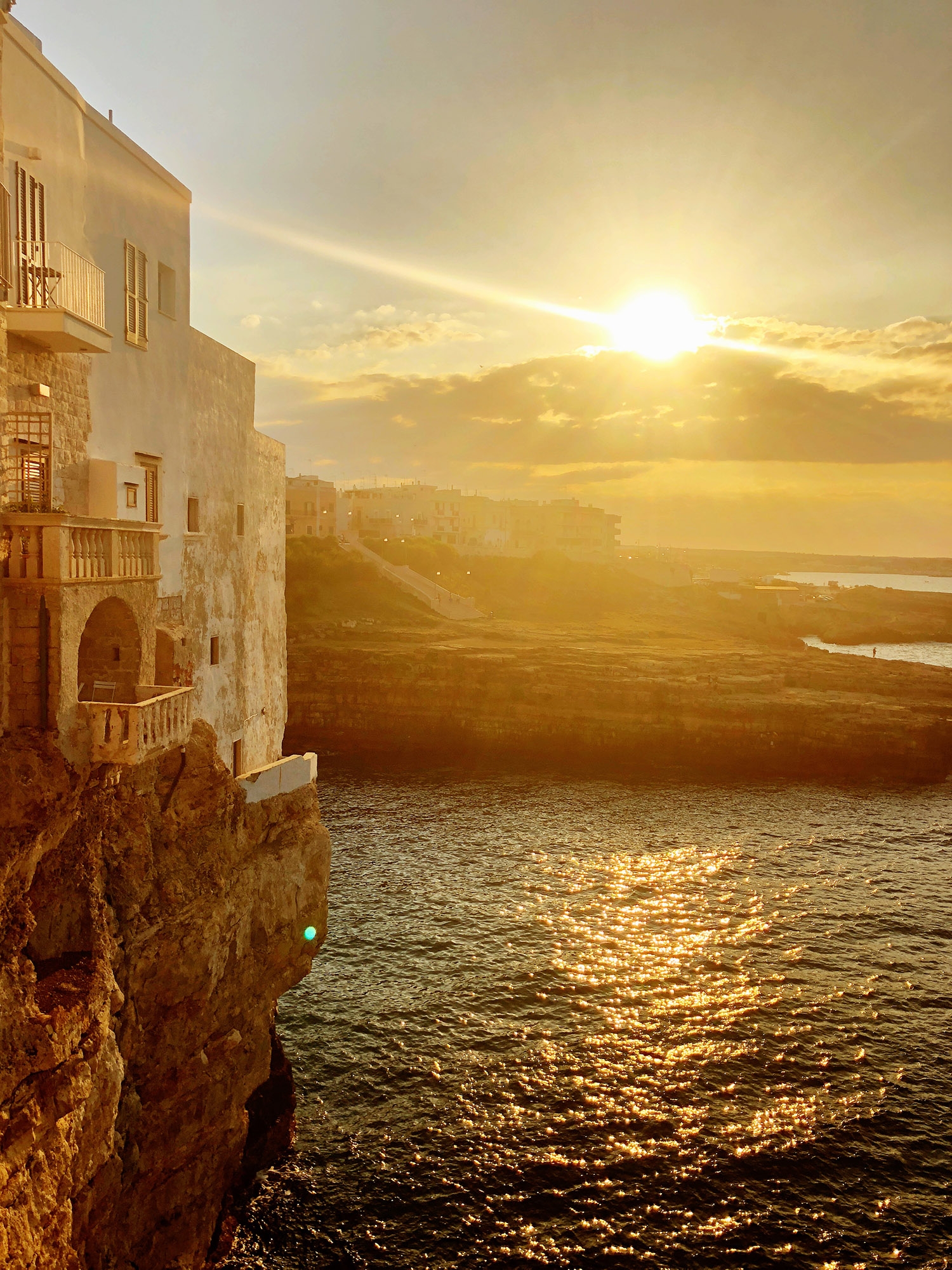 A view of the sunset on the ocean from a cliff at Polignano de Mare