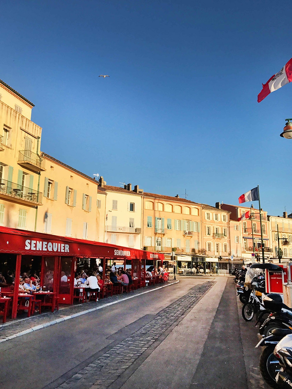Vieux Port is lined with old buildings, vespas and the French flag 