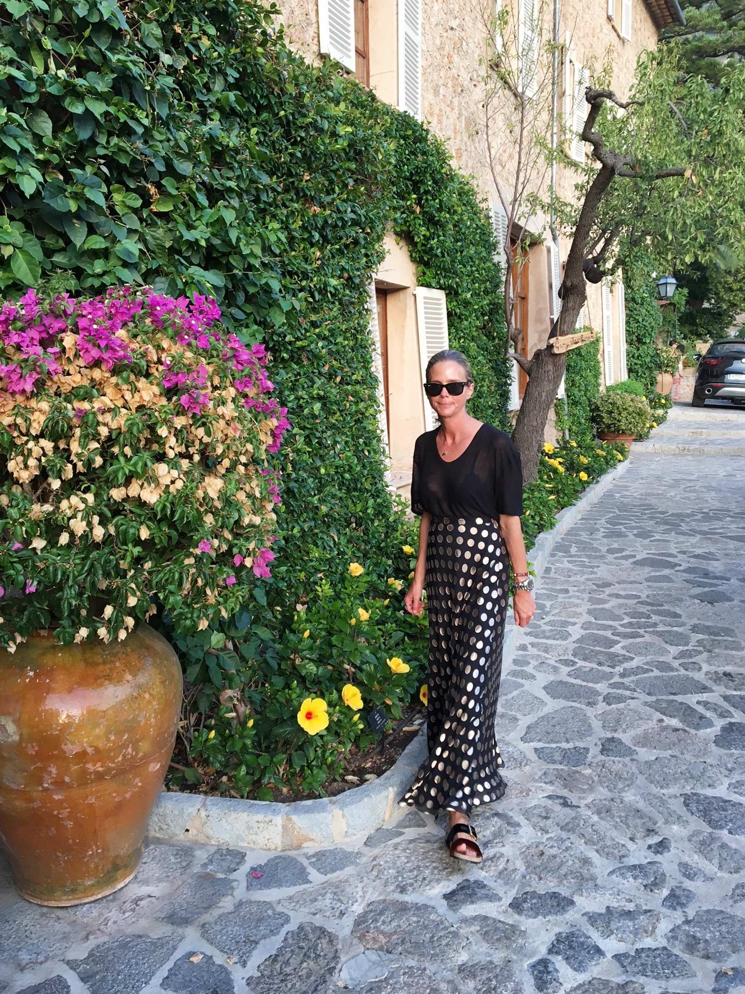Sophie Lee strolls past lush green vines, blooming flowers and old buildings on her way to dinner 